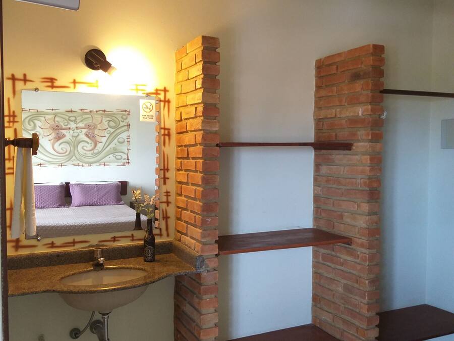 A bathroom with a sink, mirror, and a brick accent wall.