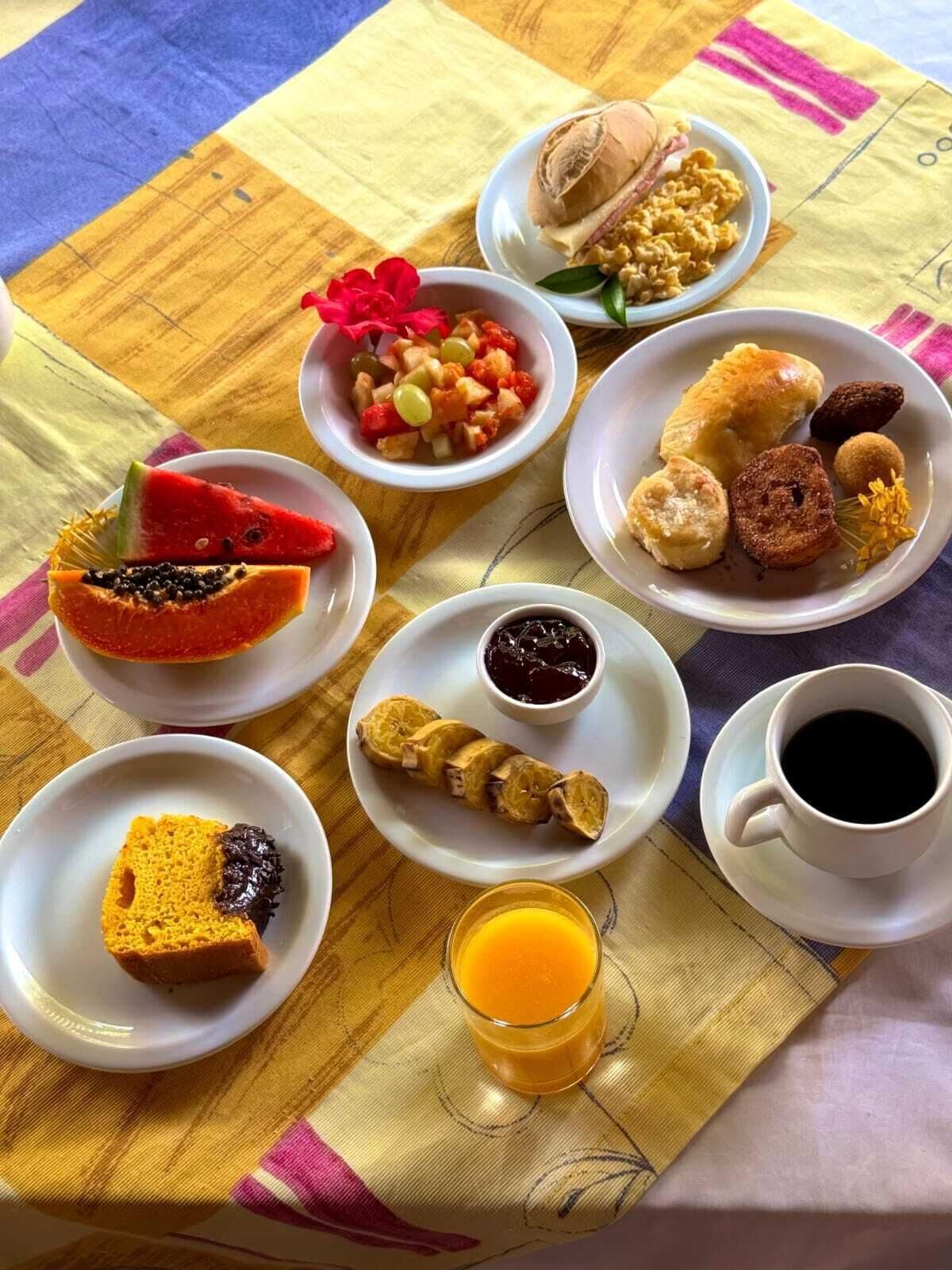 Ein Frühstückstisch mit verschiedenen Speisen, darunter Obst, Gebäck und eine Tasse Kaffee.