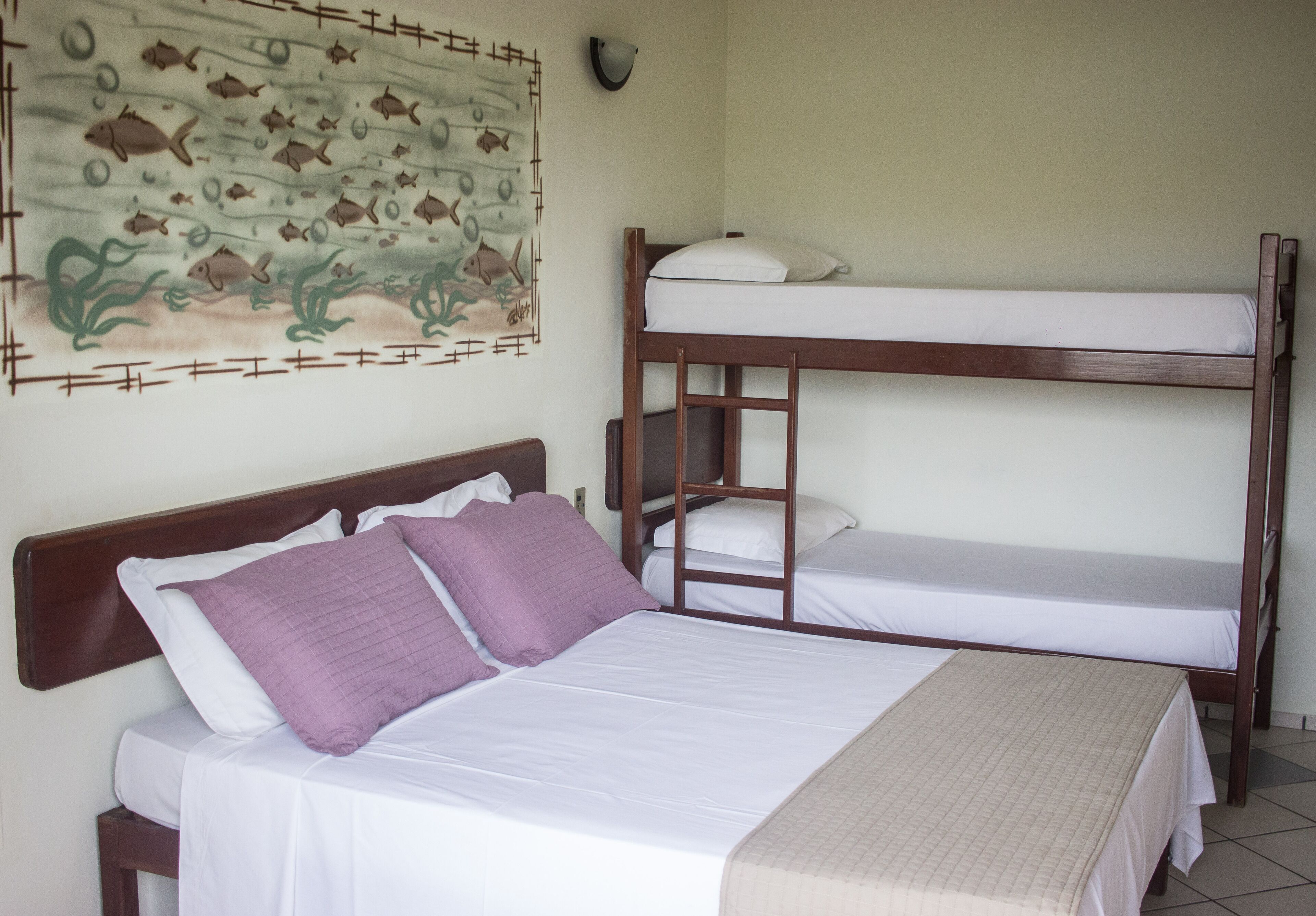 Una habitación con una cama individual, una litera y un mural en la pared.