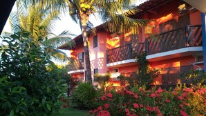 A hotel with a balcony, lush greenery, and flowering plants. - Pousada Coral de Fogo (Prado)
