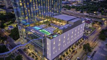 Un hotel moderno de gran altura con piscina en la azotea, varios pisos y fachada de vidrio.