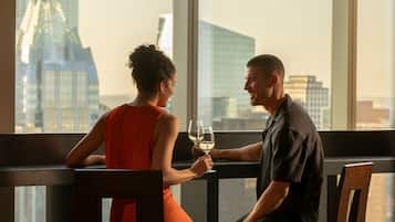 A couple sitting at a table with a city view, holding wine glasses.