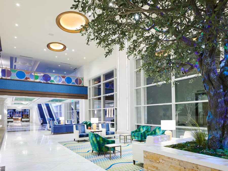 A spacious lobby with a large tree, seating areas, and a reception desk.