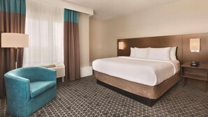 A hotel room with a bed, a chair, a nightstand, and a lamp. - Park Inn by Radisson Brampton, On (Brampton)