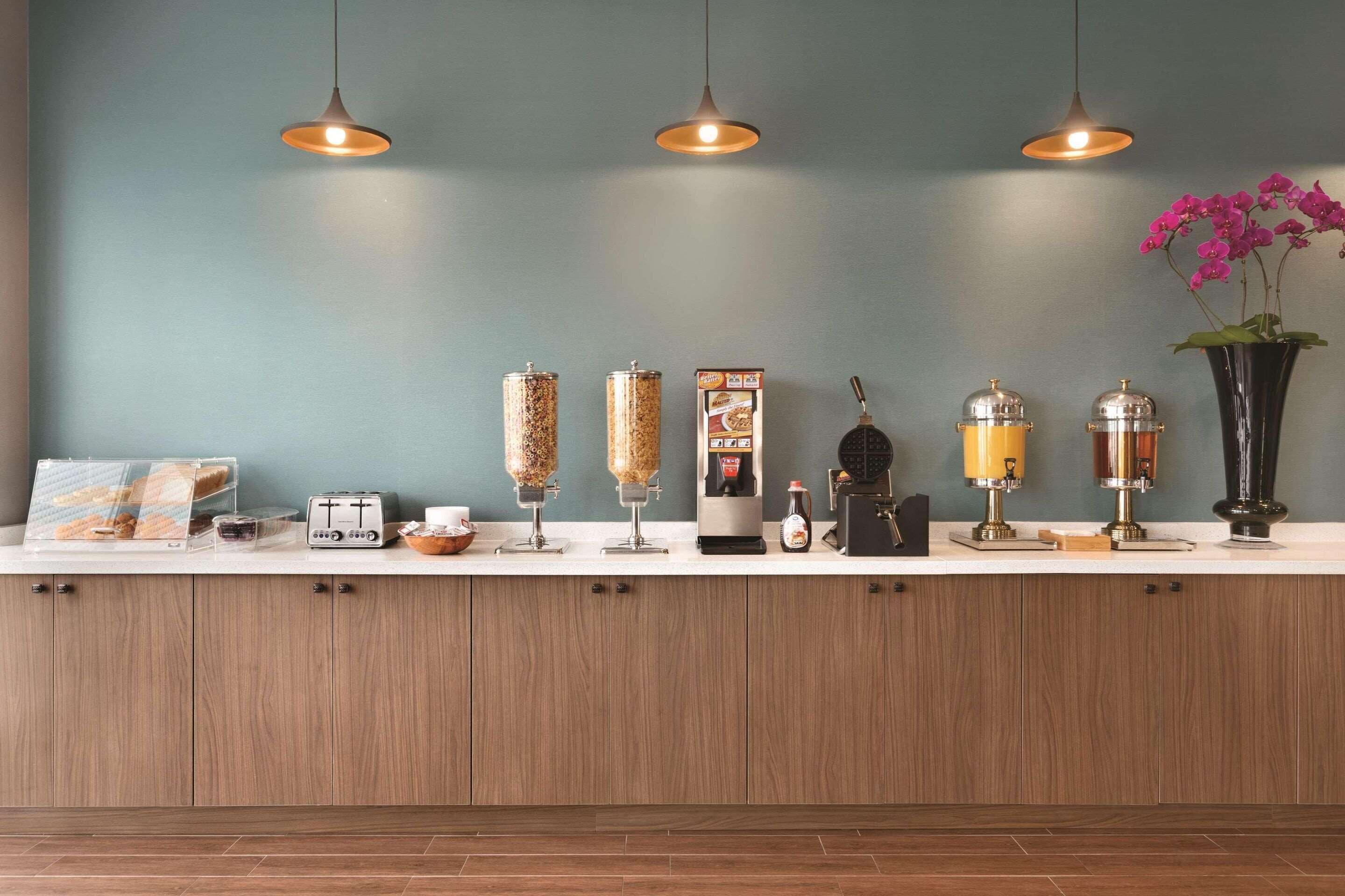 Una encimera de cocina con varios electrodomésticos y recipientes, como una cafetera, un procesador de alimentos y un panera.