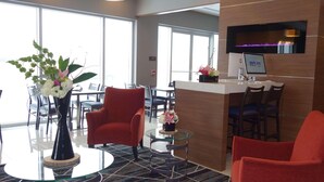 A hotel lobby with a reception desk, seating area with chairs, a vase with flowers, and large windows. - Park Inn by Radisson Brampton, On (Brampton)