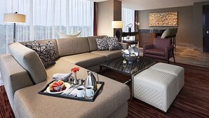 A modern hotel room with a sectional sofa, a coffee table with breakfast items, a separate armchair, and a fireplace. - Live! Casino & Hotel Maryland (Hanover)