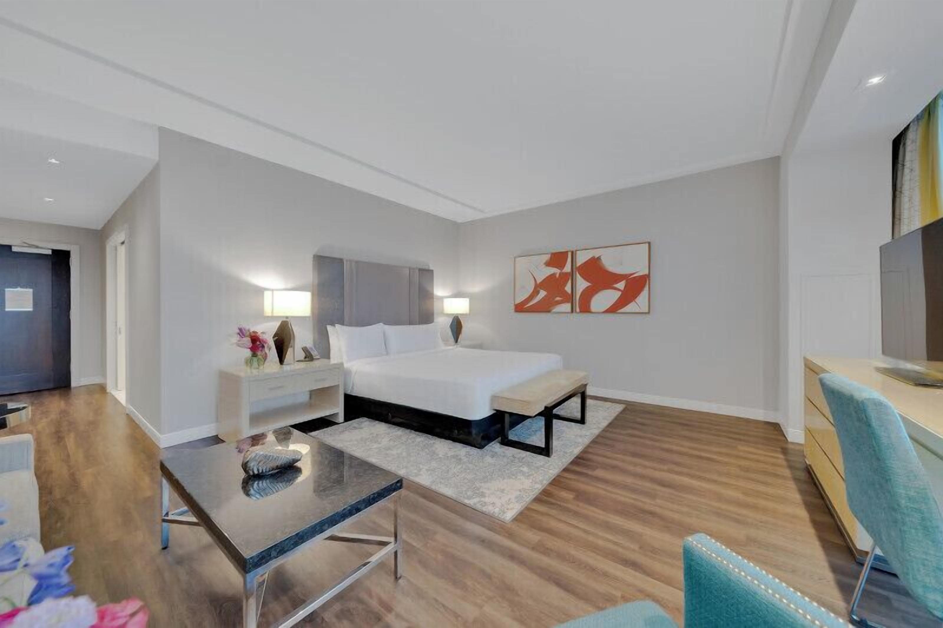 Une chambre d’hôtel moderne équipée d’un lit, d’une table de chevet, d’une lampe et d’un bureau avec une chaise.