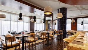 Un restaurante amplio con techos altos, iluminación colgante y una variedad de opciones de asientos, incluyendo mesas y cabinas.