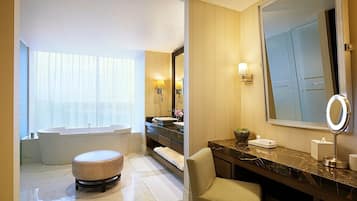 A modern bathroom with a bathtub, vanity, and large mirror.