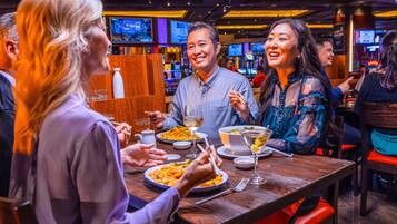 A group of people dining at a restaurant with multiple screens in the background.
