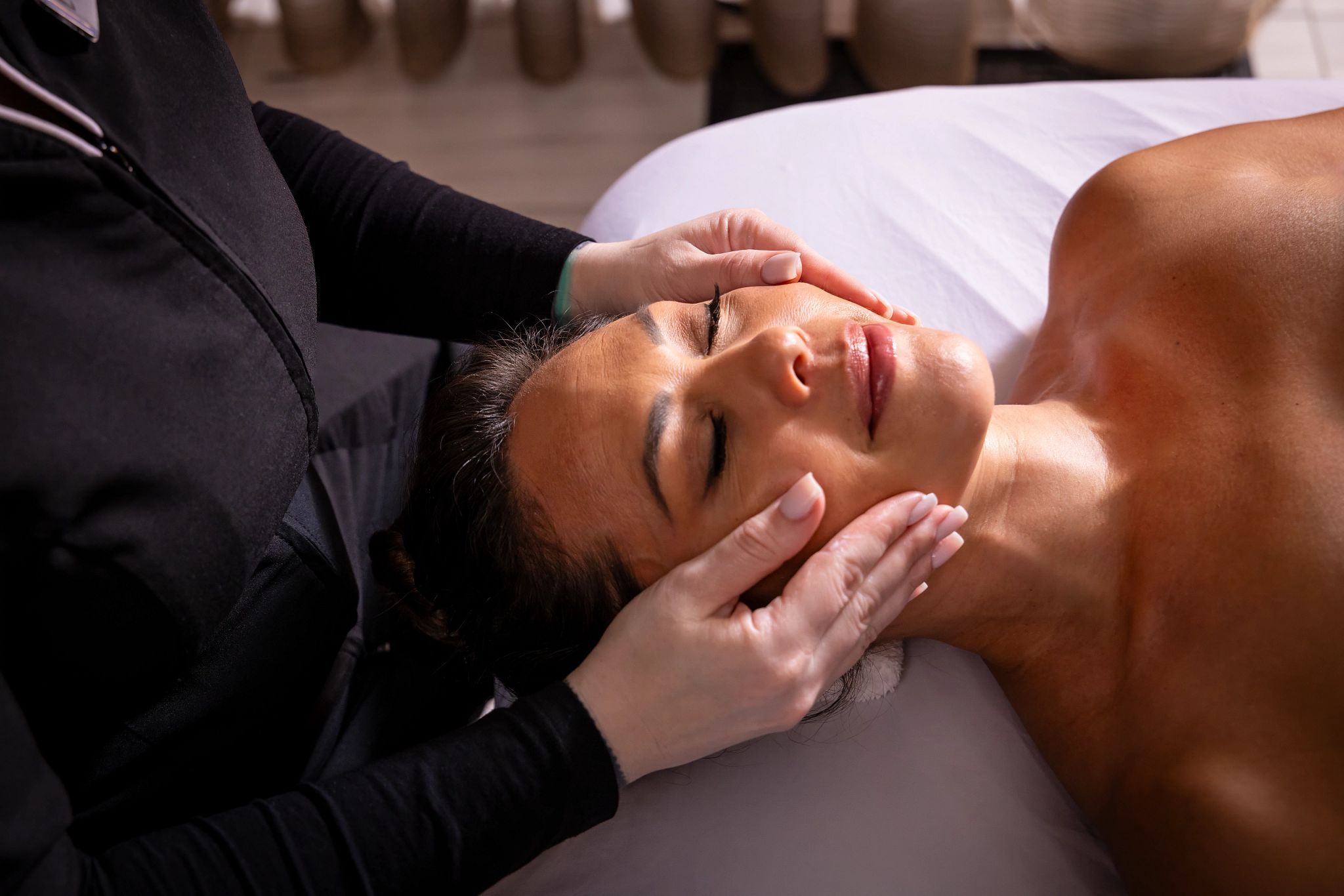 A person lying on a bed receiving a massage.