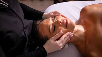 A person lying on a bed receiving a massage.