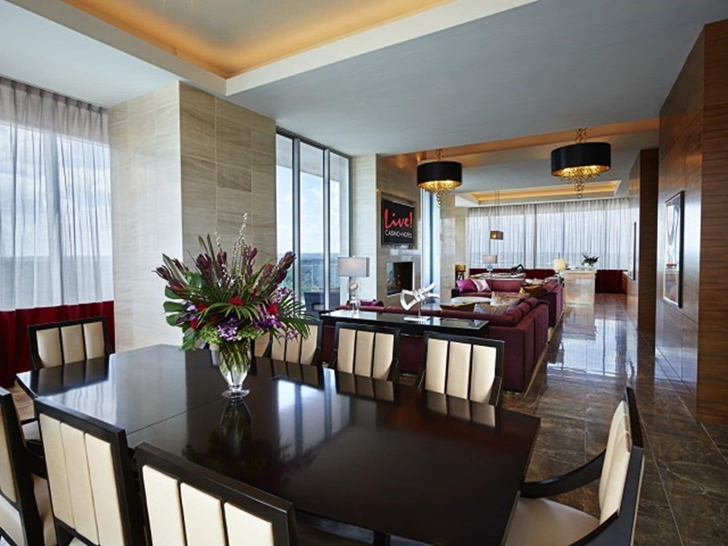 A modern hotel lobby with a dining area, a sofa set, and a large window offering a city view.