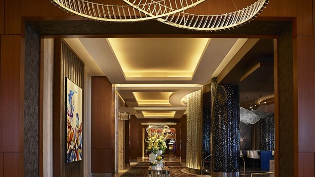 A spacious hotel lobby with a geometric patterned floor, a central reception desk, and a modern chandelier. - Live! Casino & Hotel Maryland (Hanover)