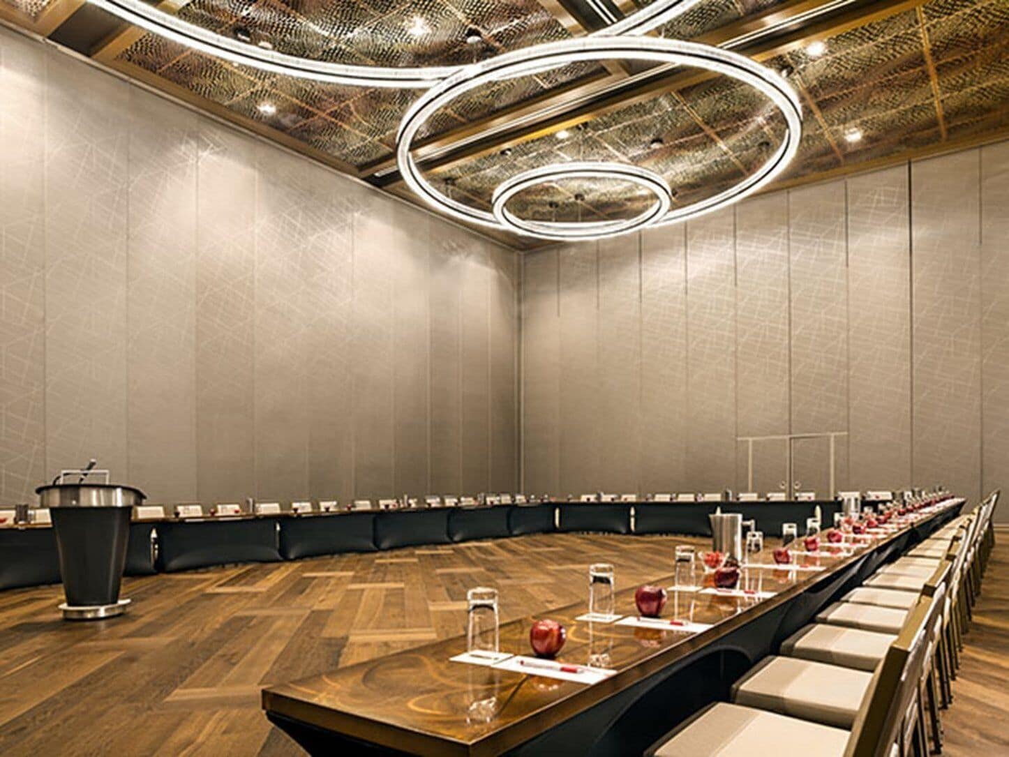 Un salón de conferencias con una larga mesa, sillas y un atril.