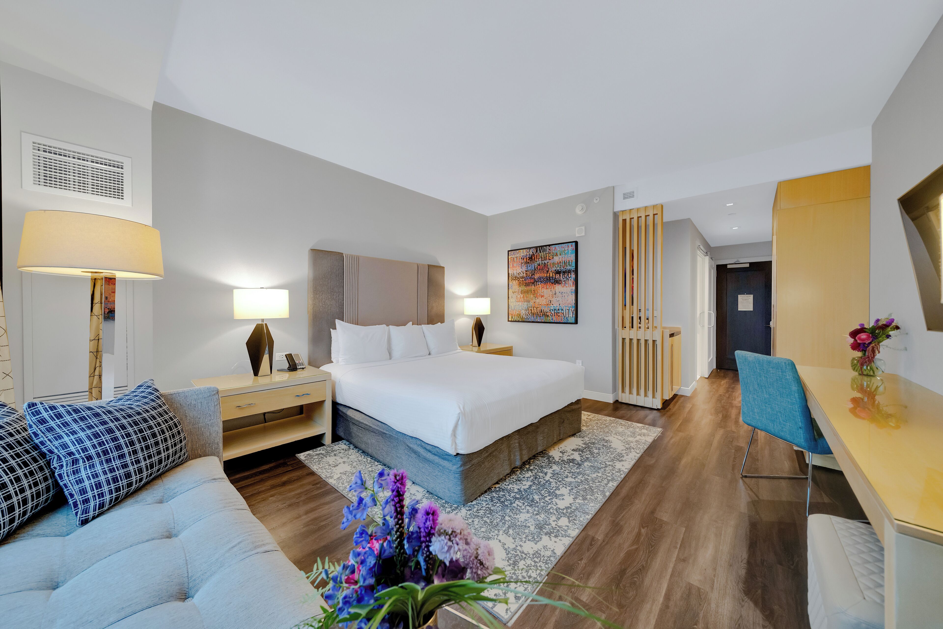 Een moderne hotelkamer met een bed, een bank, een bureau en een zithoek.