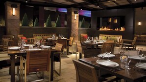 A restaurant with wooden tables and chairs, a fireplace, and decorative lighting. - Live! Casino & Hotel Maryland (Hanover)