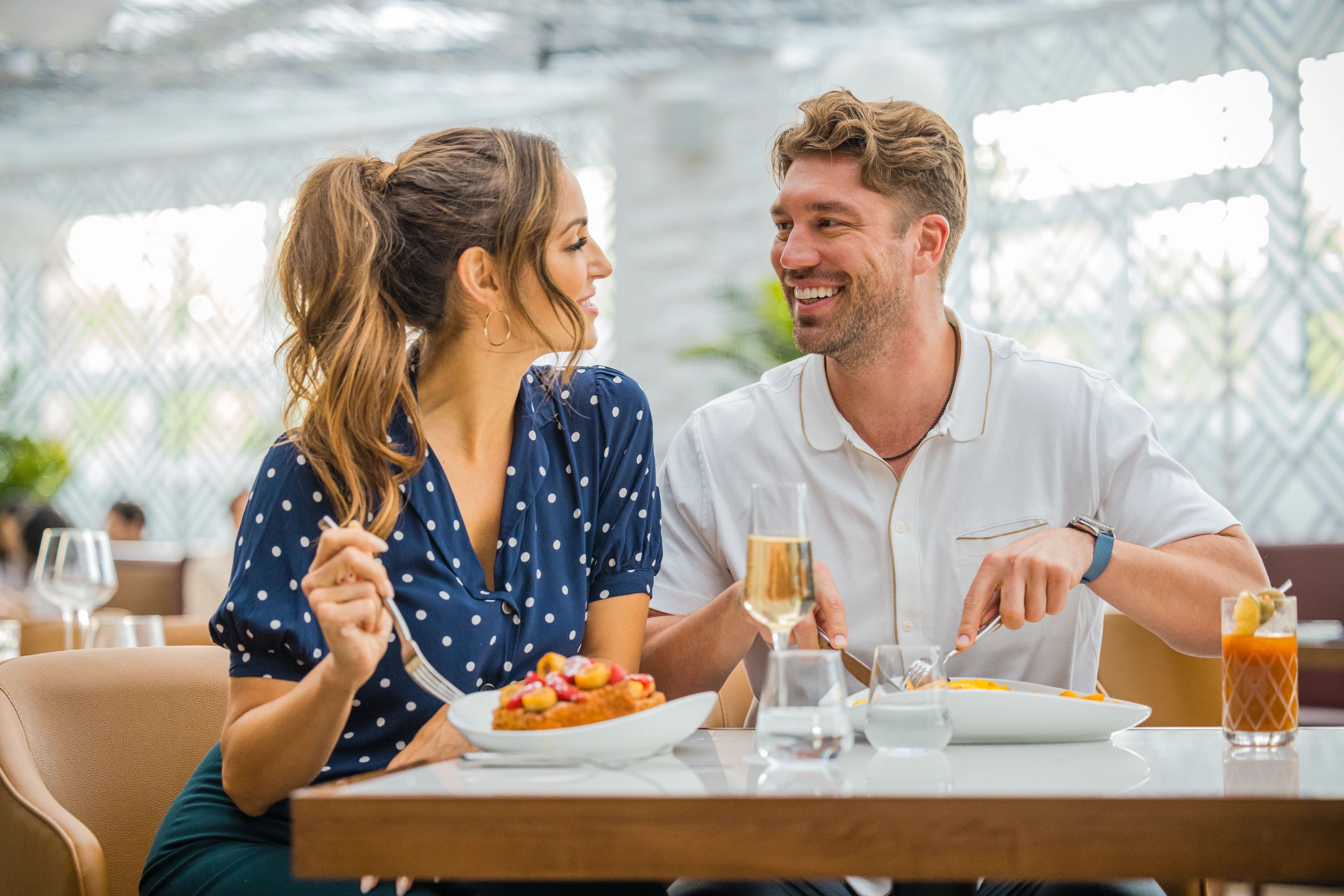 A dining table with a plate of food, a glass of wine, and a glass of orange juice.