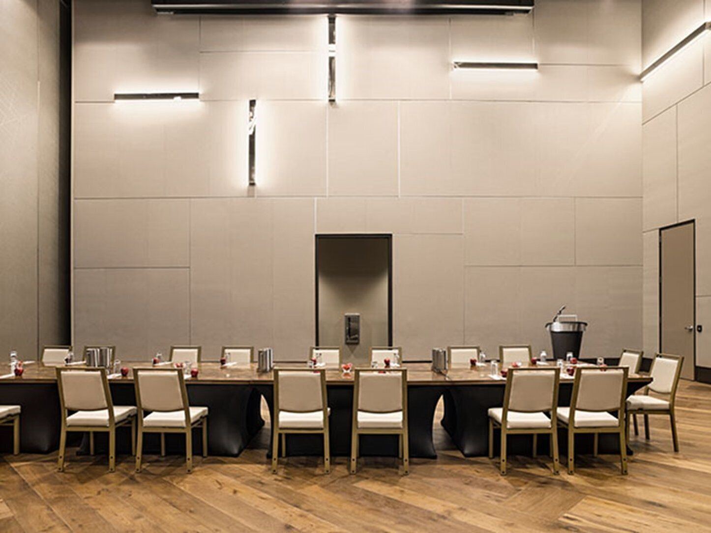 A conference room with a long table, chairs, and a trash bin.