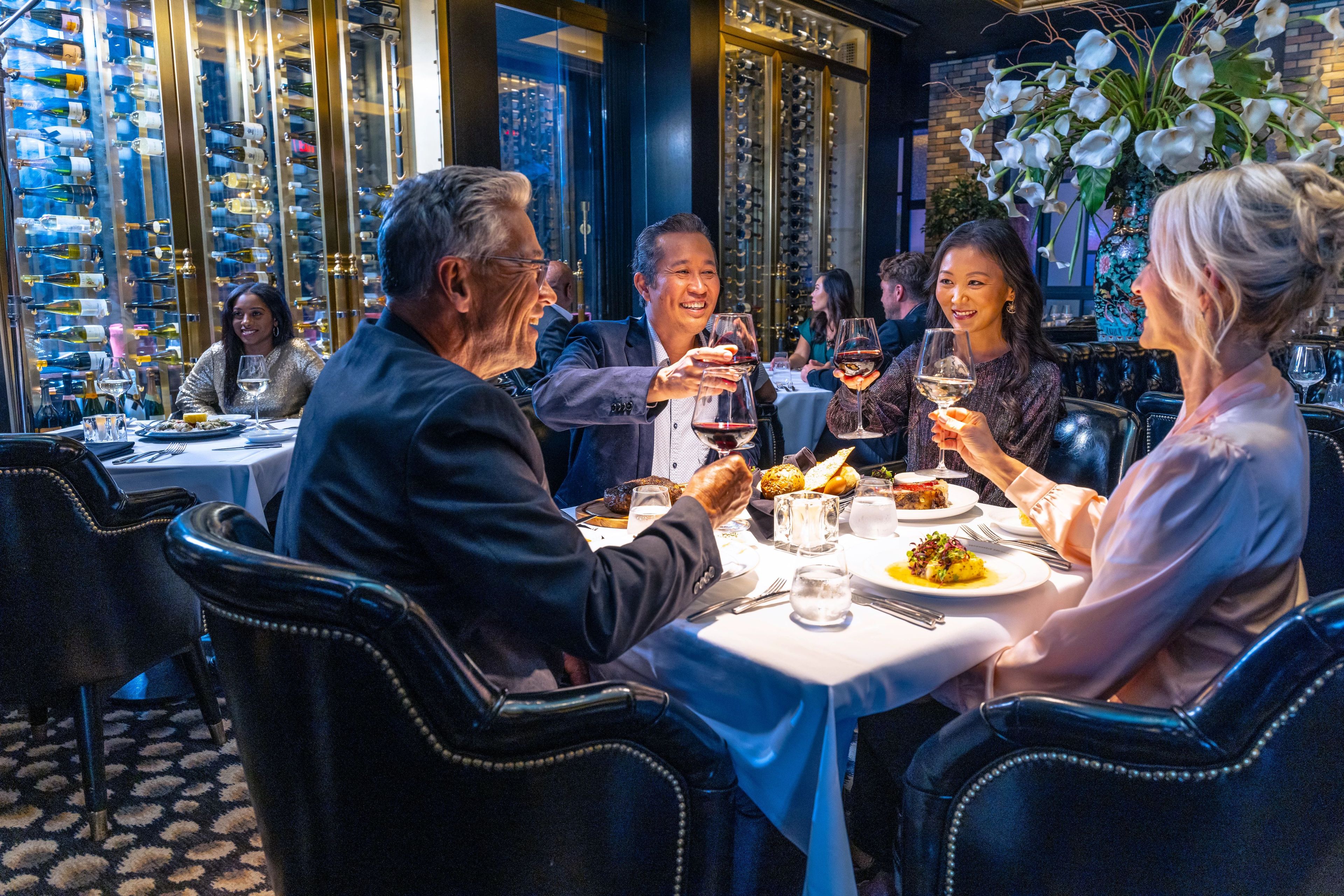 A group of people dining at a restaurant with a wine rack in the background.