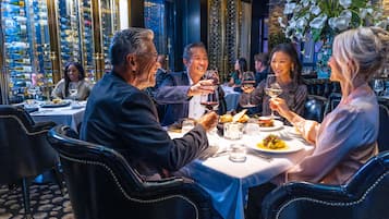 A group of people dining at a restaurant with a wine rack in the background.