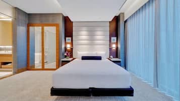 Habitación de hotel moderna con una cama grande, cabina de ducha de vidrio y vistas a la ciudad.