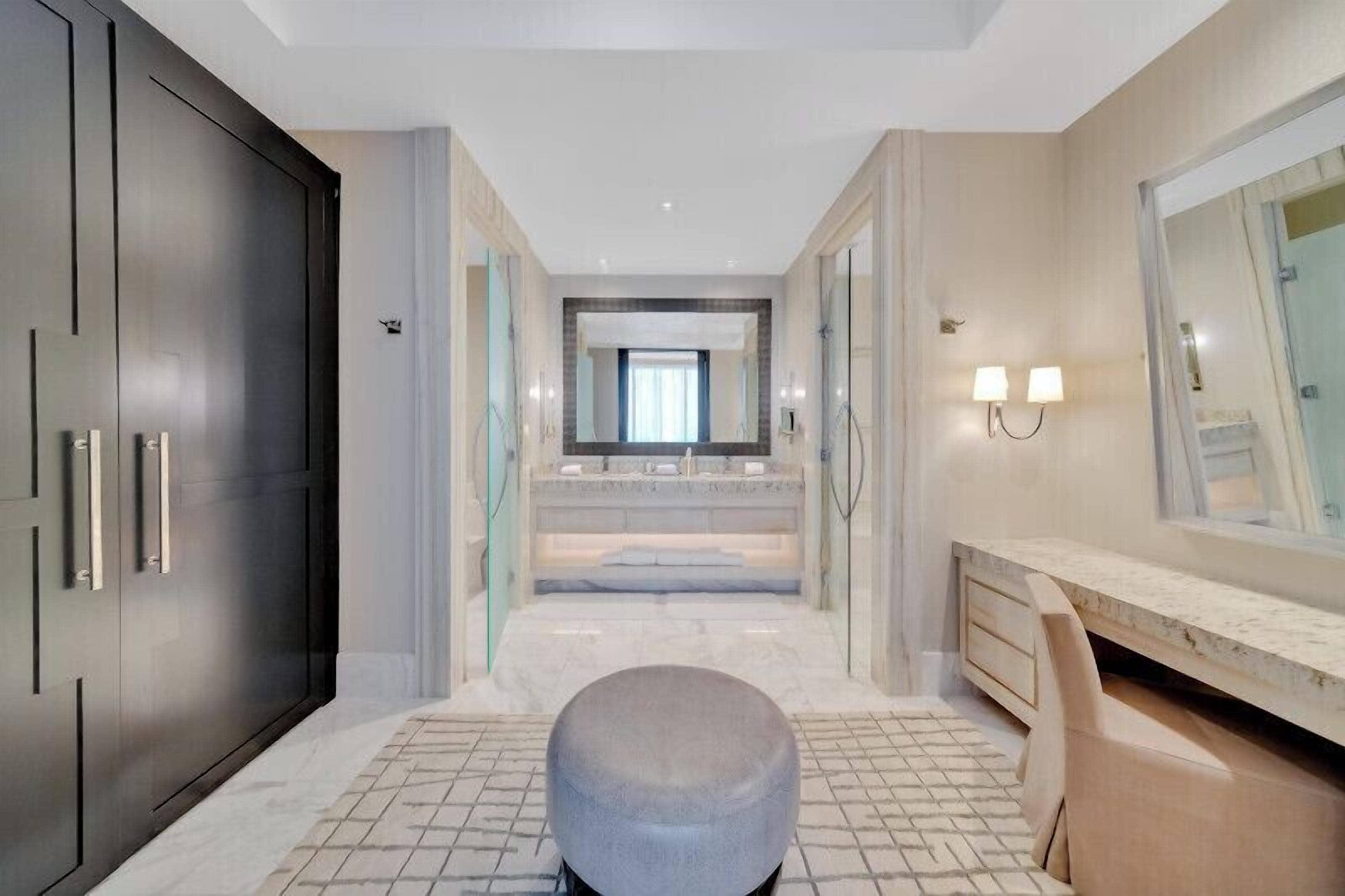 A modern bathroom with a large mirror, a vanity, and a marble floor.