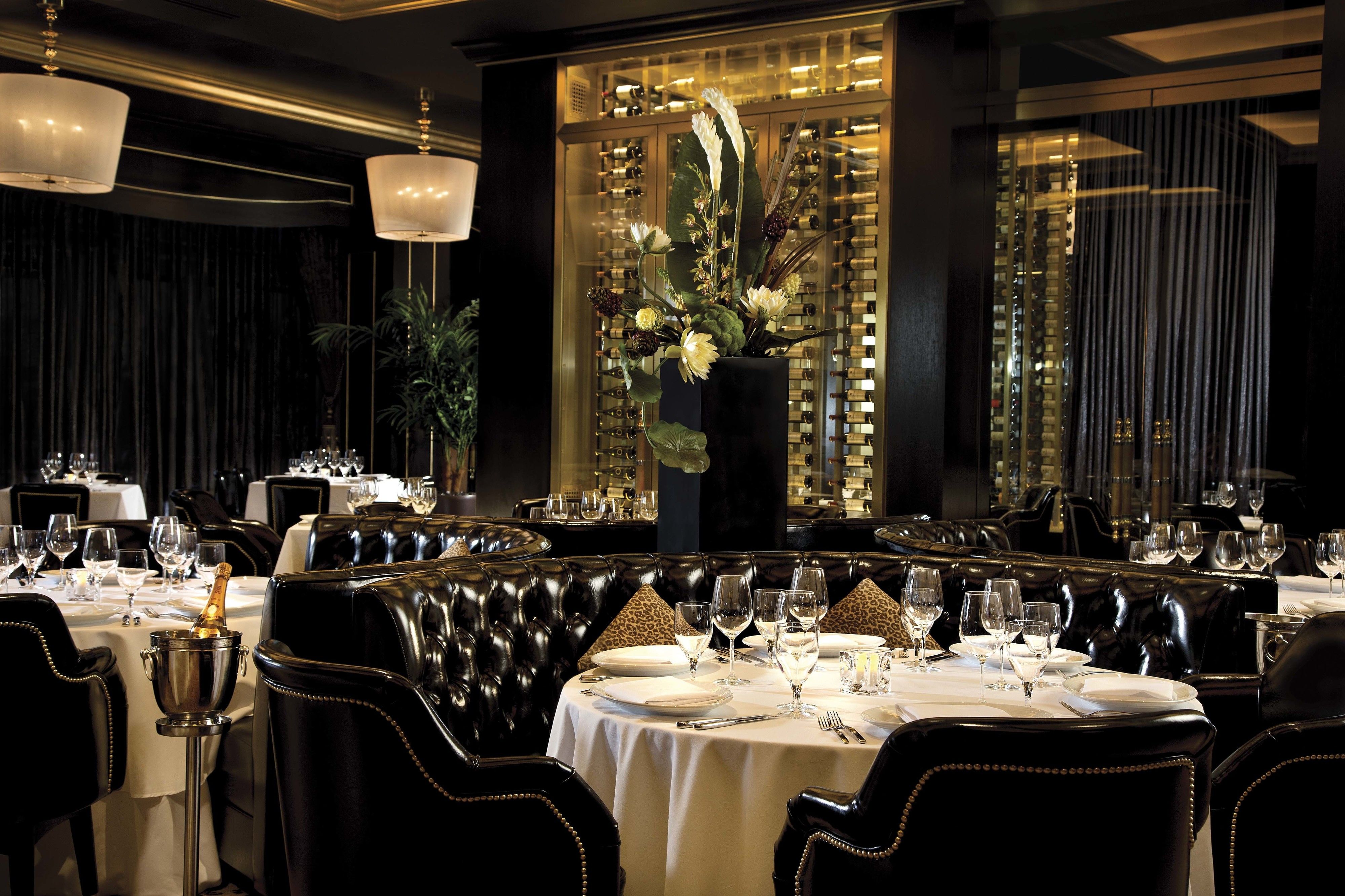 Un comedor lujoso con asientos de cuero, manteles blancos y un gran centro de mesa floral.