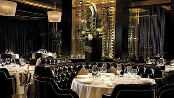 Un comedor lujoso con asientos de cuero, manteles blancos y un gran centro de mesa floral.