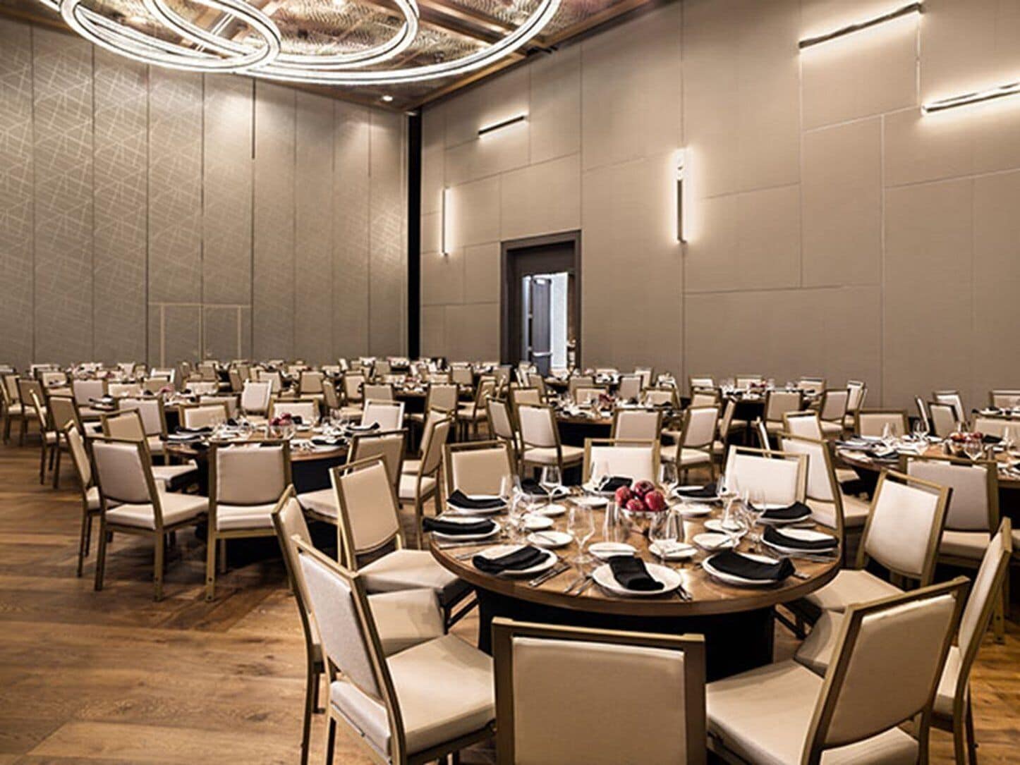 Une grande salle de conférence dotée de tables rondes, de chaises et d’un lustre moderne.