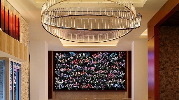 A modern lobby with a large chandelier, a floral wall display, and a geometric patterned floor. - Live! Casino & Hotel Maryland (Hanover)