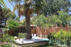 A pool area with a stone deck, palm trees, and a wooden fence. - Palace Hotel Costa Del Sole (Catania)