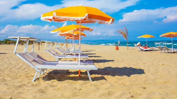 A beach with rows of sun loungers and orange umbrellas. - Palace Hotel Costa Del Sole (Catania)