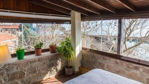 A balcony with potted plants, a bed, and a view of buildings and trees. - Assos Yildiz Hotel (Ayvacik)