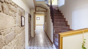 A hallway with patterned floor tiles, a stone wall, and a staircase with a metal railing. - Assos Yildiz Hotel (Ayvacik)