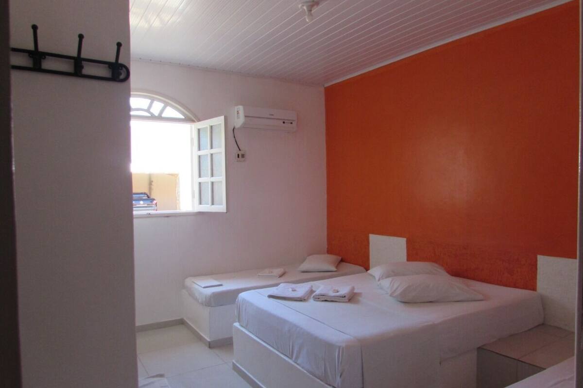 Un dormitorio con dos camas, una ventana con vistas y un equipo de aire acondicionado en la pared.