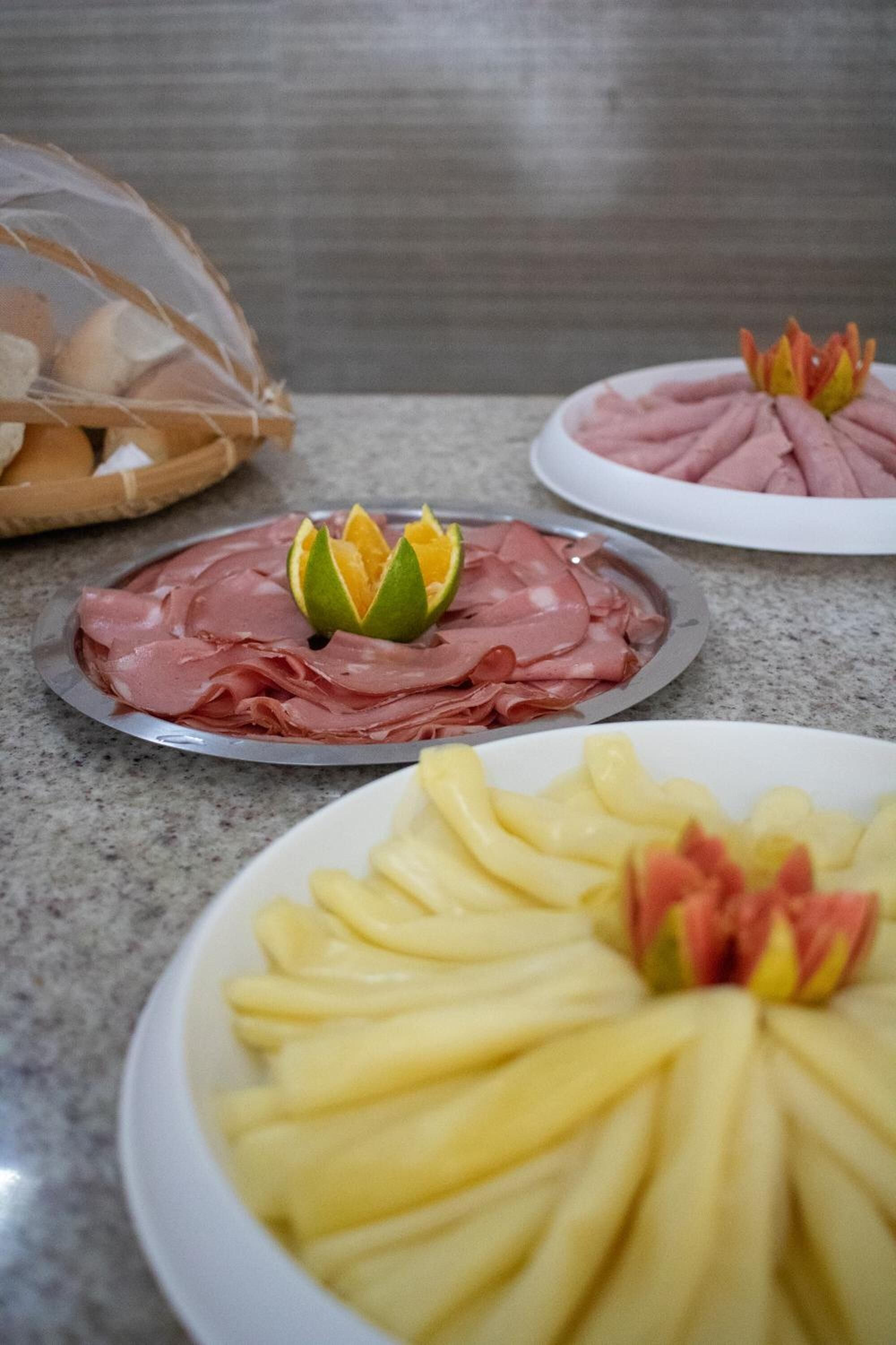 Uma mesa com alimentos bem organizados, incluindo carnes fatiadas e frutas, possivelmente para um buffet ou refeição.