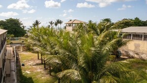 Een binnenplaats met palmboompjes, een prieel en een gebouw met een pannendak.