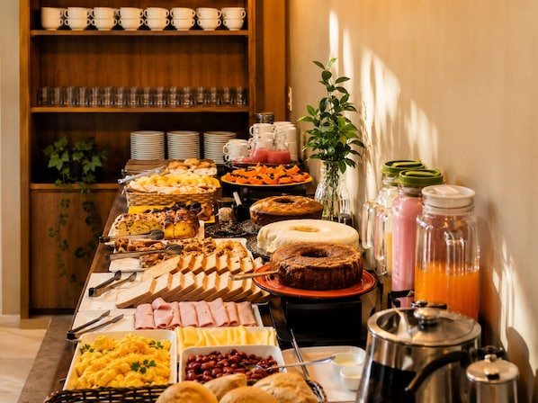 A buffet with various food items, a coffee station, and a plant.
