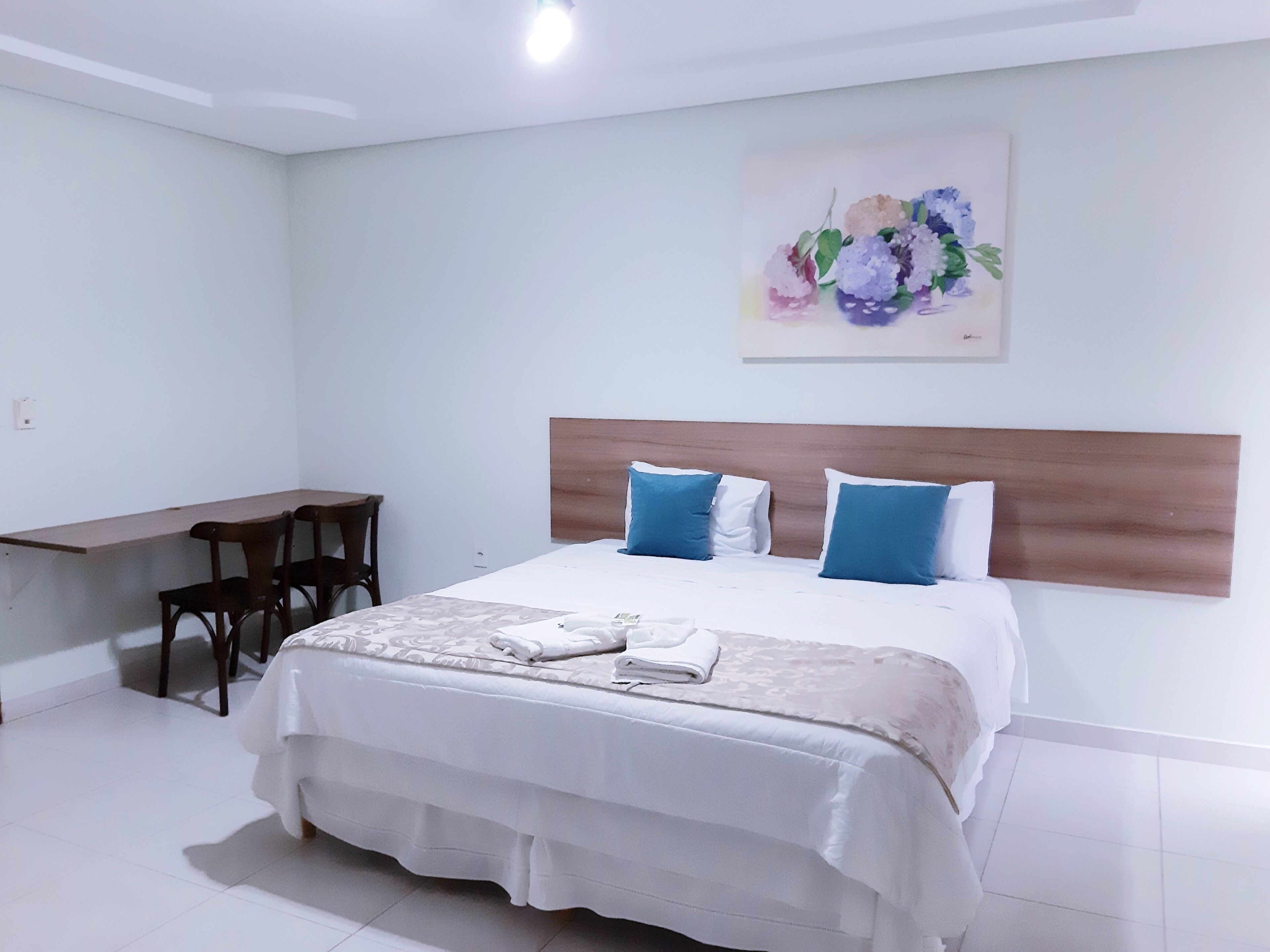 A bedroom with a bed, a desk, and chairs.