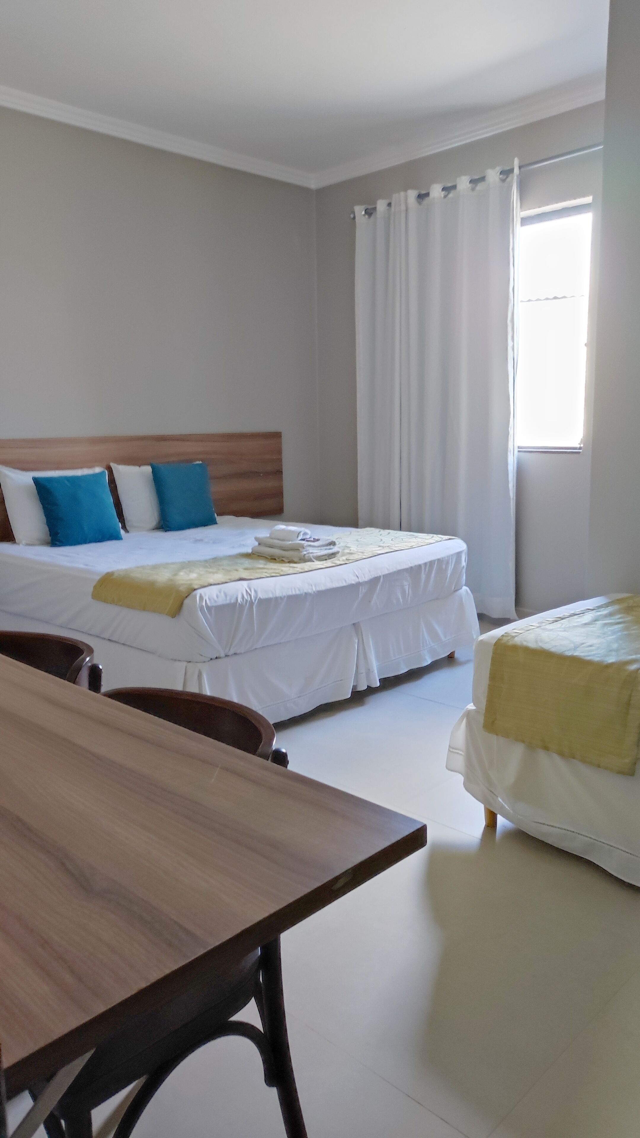 Ein Hotelzimmer mit zwei Betten, einem Holztisch und einem Fenster mit Vorhängen.