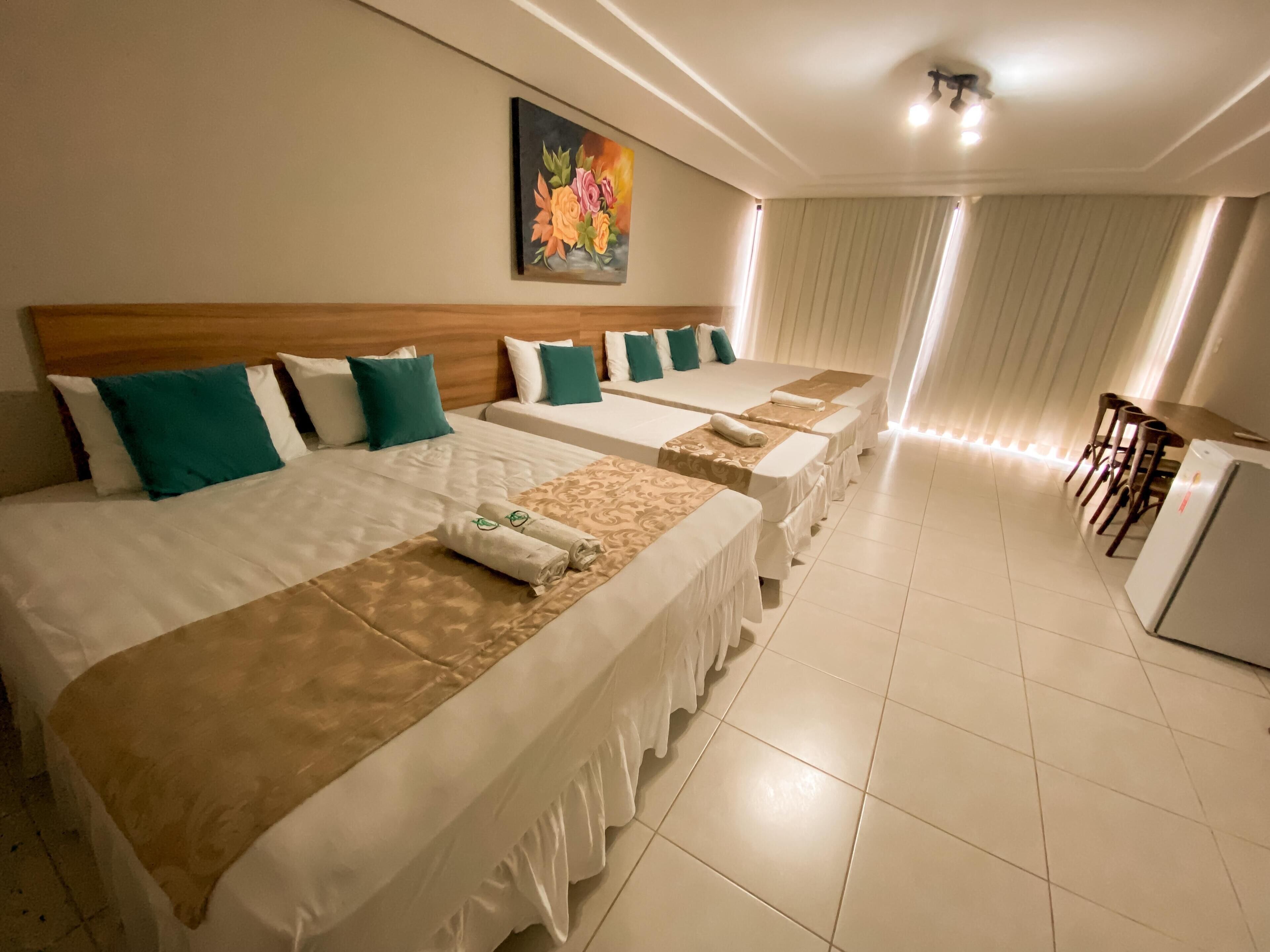 Una camera d'albergo con quattro letti, un'area pranzo e un quadro appeso al muro.