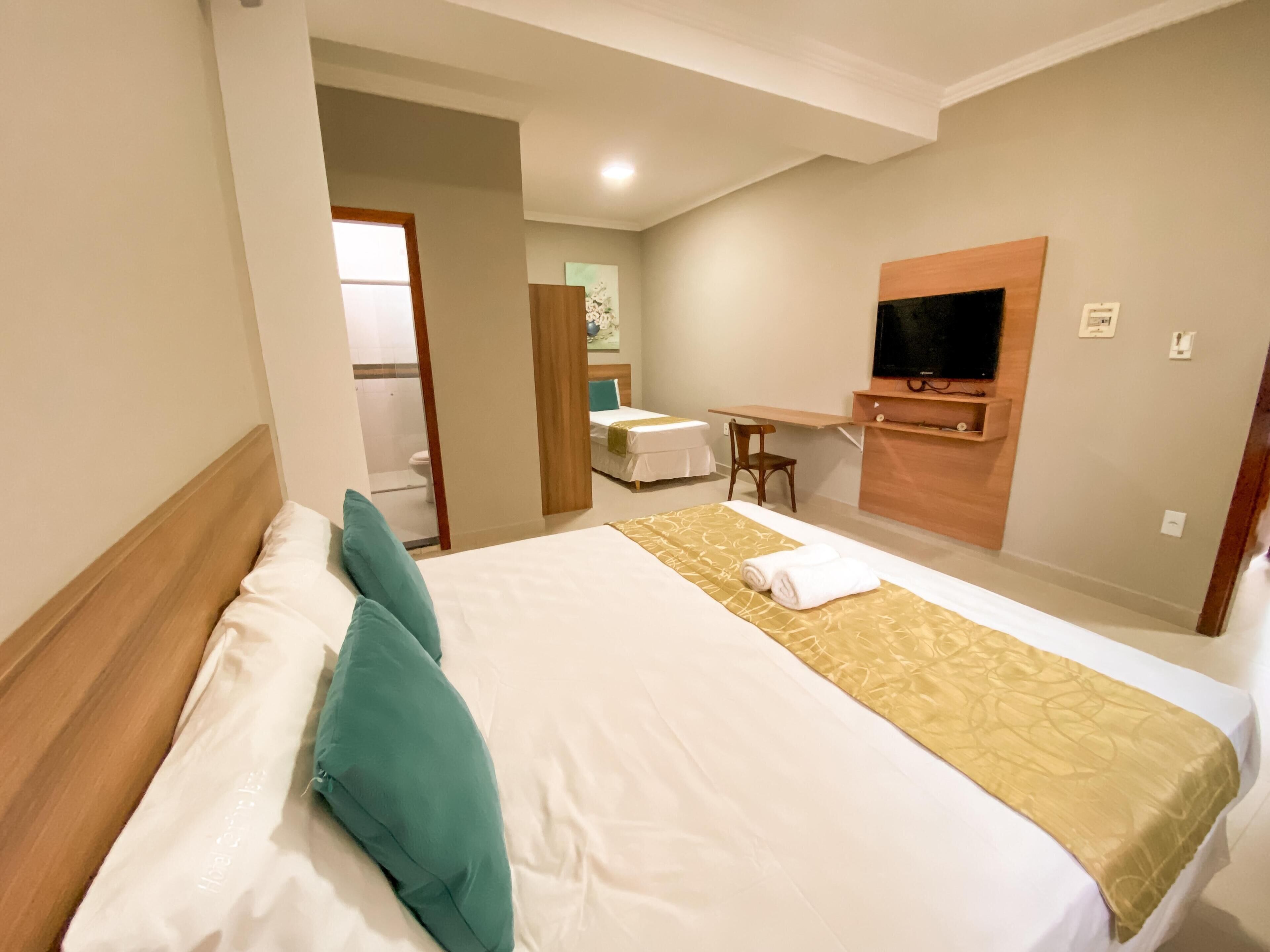 Une chambre d’hôtel équipée d’un lit, d’un bureau, d’une télévision et d’un espace douche.