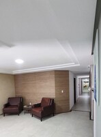 Un vestíbulo de hotel con dos sillones de cuero, una mesita y una pared de acento de madera. Un pasillo conduce a otras áreas.