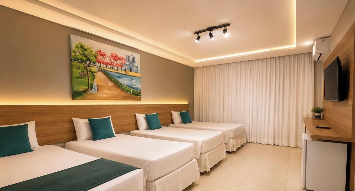 A hotel room with three beds, a painting on the wall, a television, and a small refrigerator.