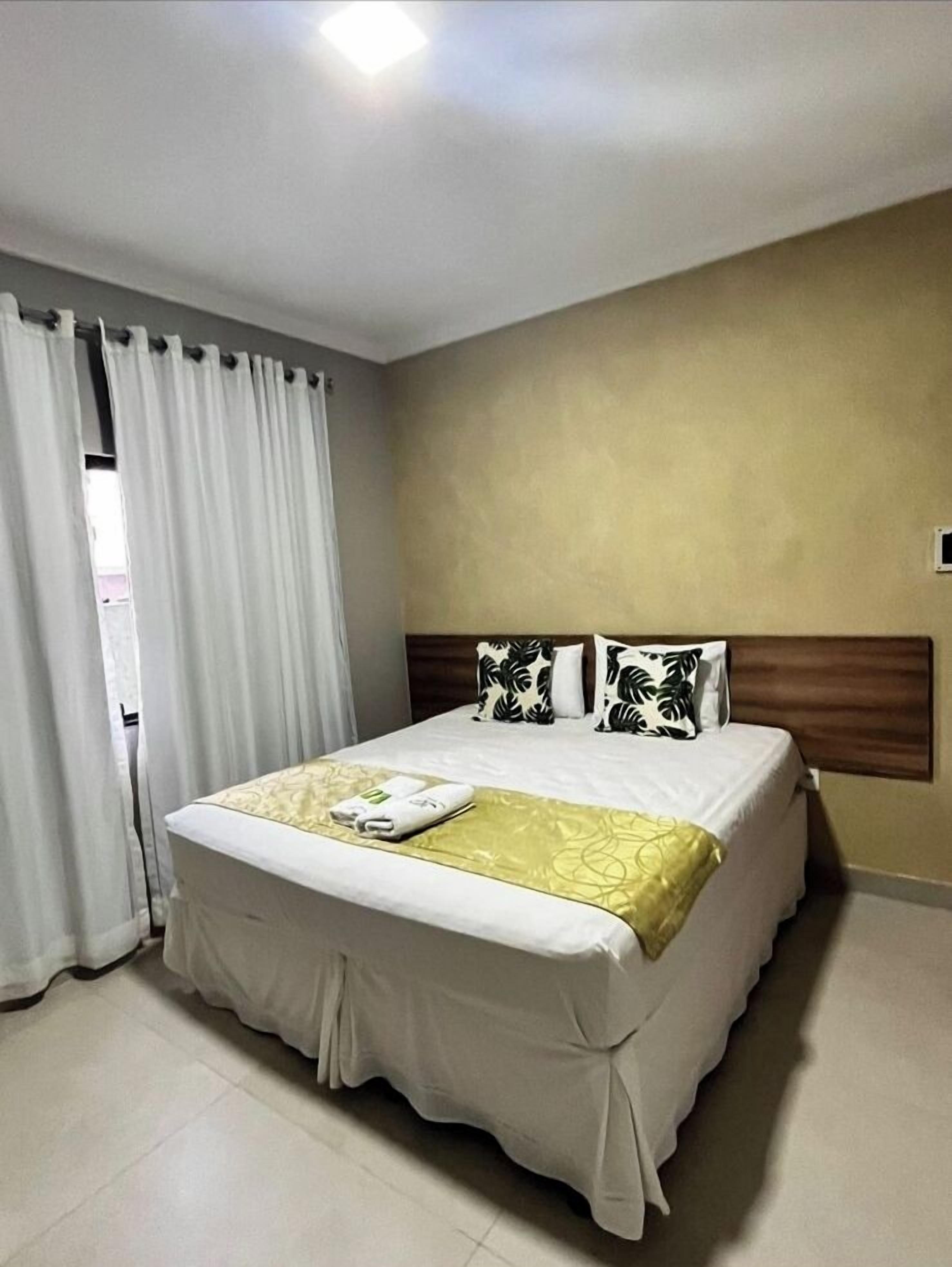 Una habitación de hotel con una cama grande, un cabecero de madera y una cortina en la ventana.