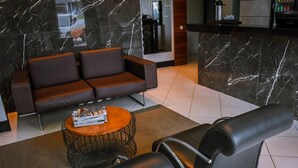 A modern lobby with a marble reception desk, a sofa, and a coffee table. - Pioneiro Hotel (Teixeira de Freitas)