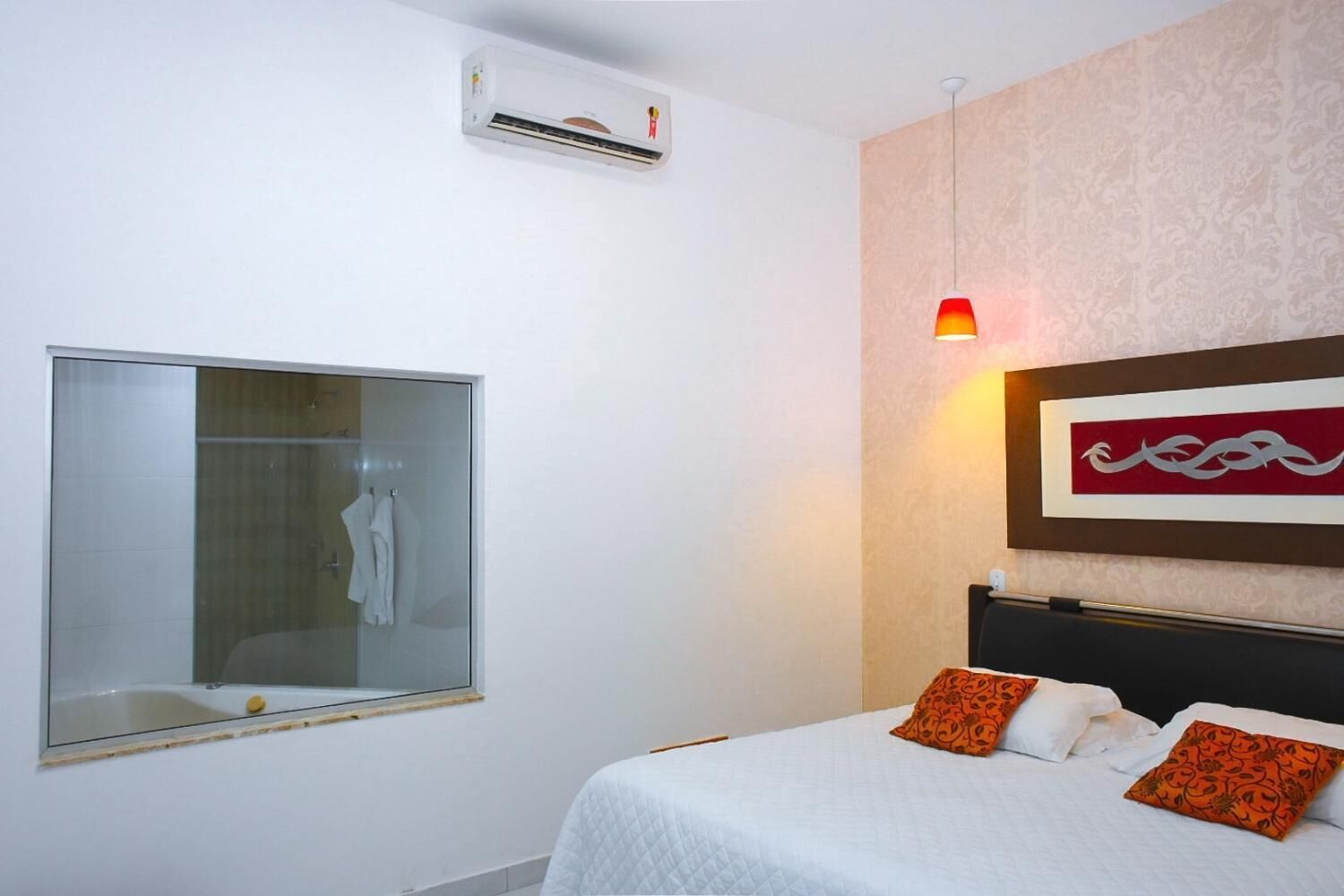 Une chambre d’hôtel équipée d’un lit, d’une douche et d’un climatiseur fixé au mur.