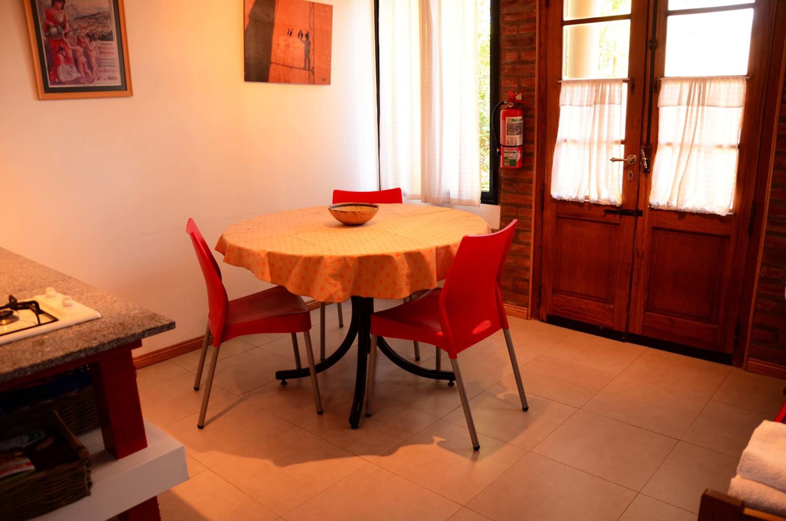 Un comedor con una mesa redonda, sillas rojas y un tazón sobre la mesa.